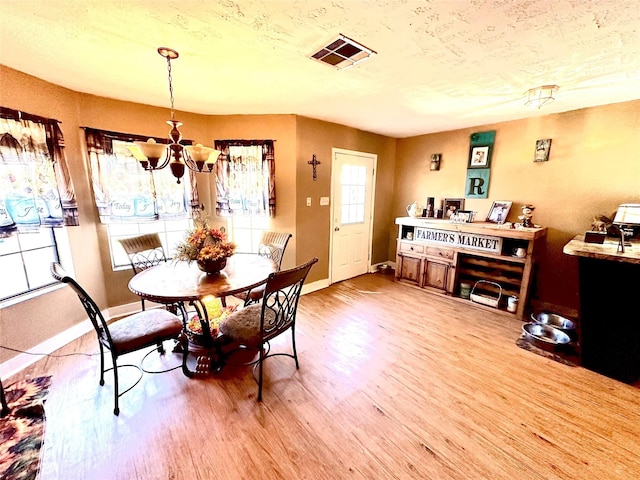 dining area with hardwood / wood-style flooring, a notable chandelier, and a healthy amount of sunlight