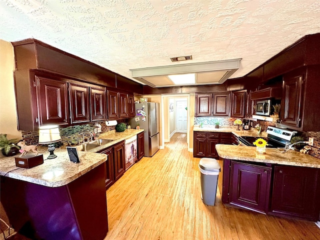 kitchen featuring kitchen peninsula, light wood-type flooring, stainless steel appliances, and a breakfast bar area