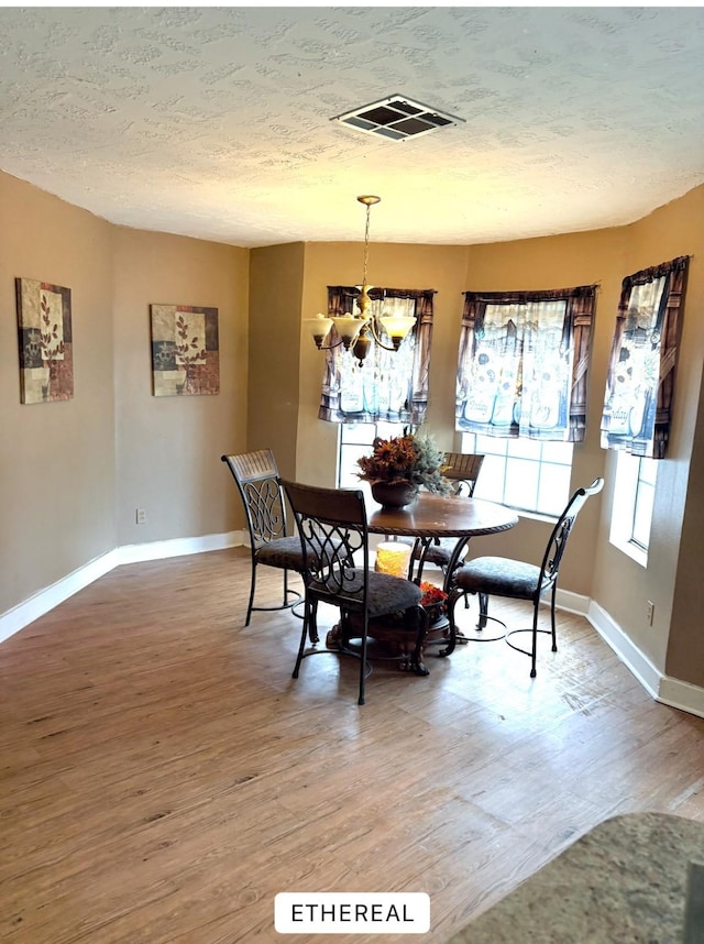 dining area featuring hardwood / wood-style floors, a textured ceiling, and an inviting chandelier