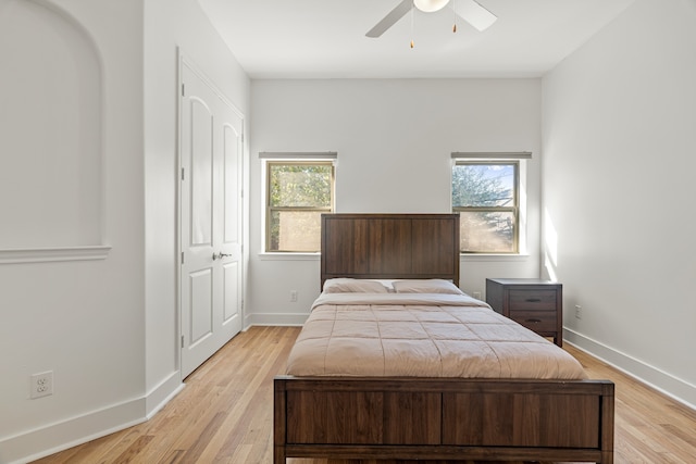 bedroom with multiple windows, ceiling fan, a closet, and light hardwood / wood-style floors