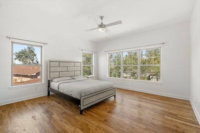 bedroom featuring multiple windows, wood-type flooring, and ceiling fan