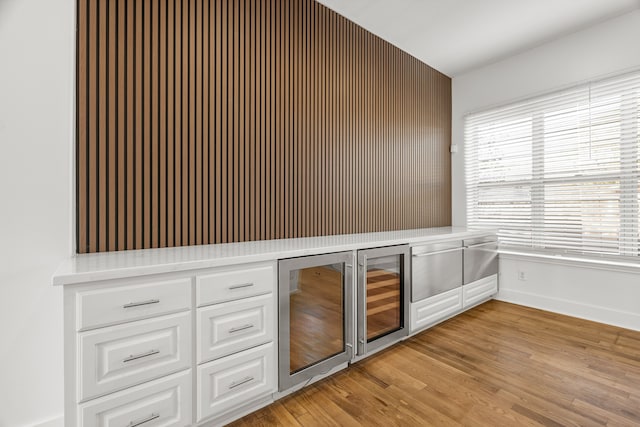 bar featuring white cabinets, beverage cooler, and light wood-type flooring