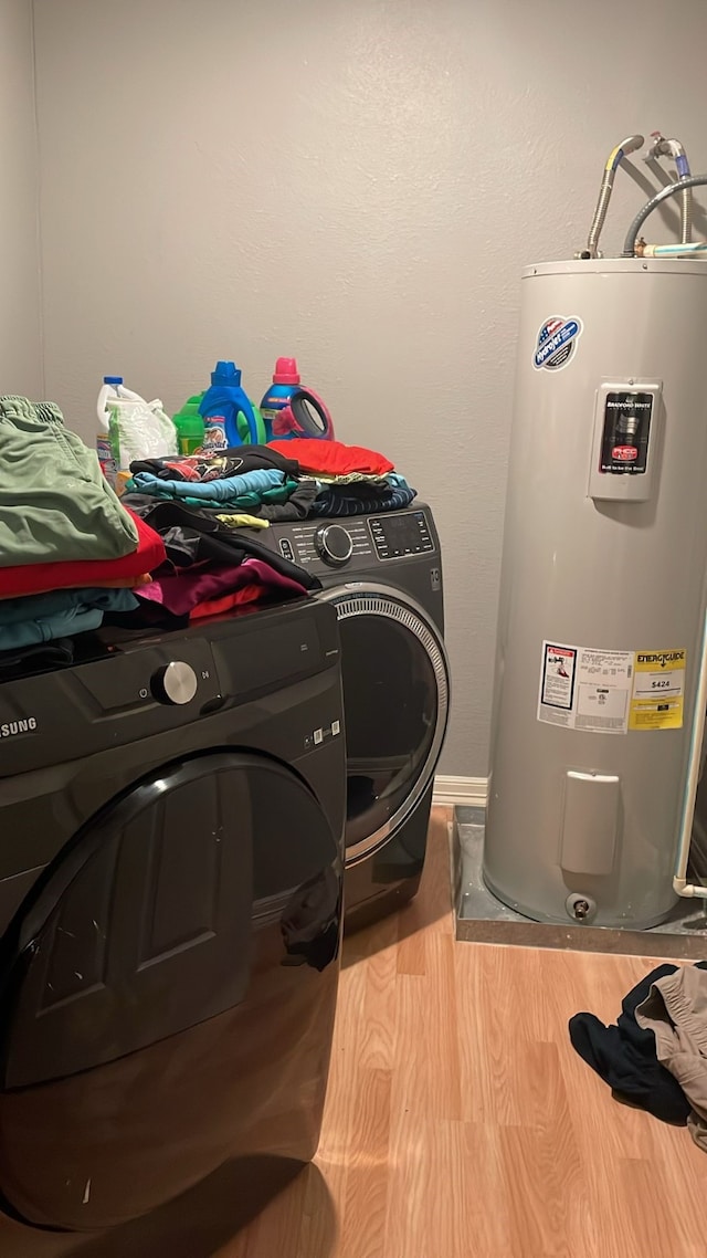 clothes washing area with washer / dryer, electric water heater, and hardwood / wood-style flooring