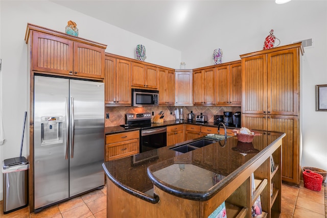 kitchen featuring backsplash, appliances with stainless steel finishes, sink, and a center island with sink