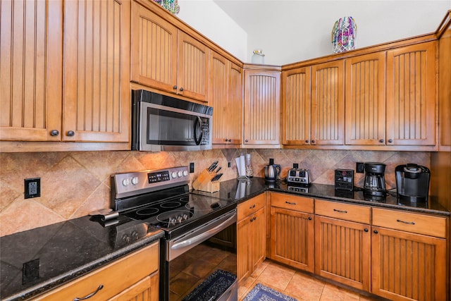 kitchen featuring dark stone counters, light tile patterned floors, decorative backsplash, and appliances with stainless steel finishes