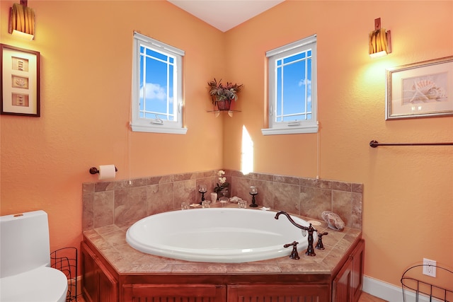 bathroom with toilet, plenty of natural light, and a tub