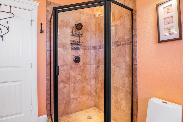 bathroom featuring toilet and a shower with door