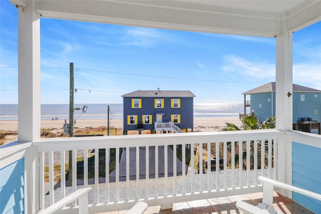 wooden terrace featuring a water view and a beach view