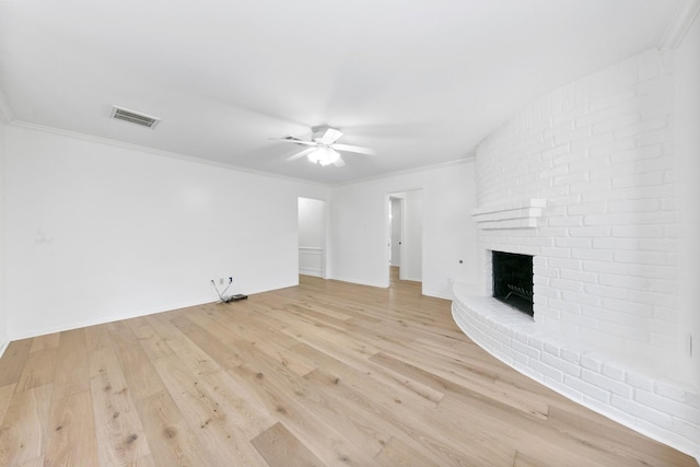 unfurnished living room featuring ceiling fan, crown molding, light hardwood / wood-style flooring, and a brick fireplace