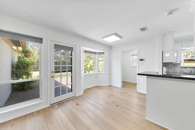 interior space with light wood-type flooring, crown molding, and a wealth of natural light