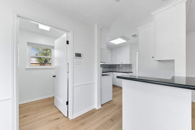 kitchen with white cabinets, light hardwood / wood-style floors, kitchen peninsula, and backsplash