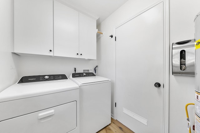 clothes washing area with cabinets, independent washer and dryer, and light hardwood / wood-style flooring