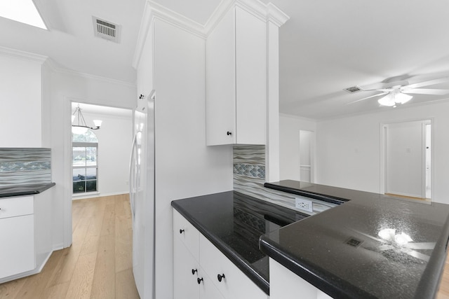 kitchen featuring ceiling fan with notable chandelier, backsplash, light hardwood / wood-style floors, and white cabinetry