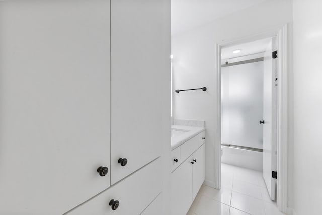 bathroom featuring tile patterned flooring, vanity, and combined bath / shower with glass door