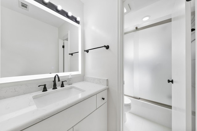 full bathroom featuring vanity, bath / shower combo with glass door, and toilet