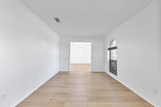 unfurnished room featuring light wood-type flooring, ornamental molding, and an inviting chandelier