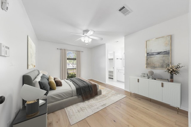 bedroom featuring light wood-type flooring, connected bathroom, and ceiling fan