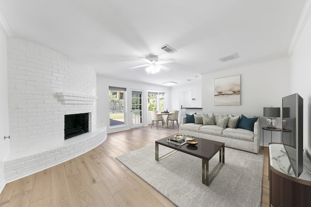 living room with ceiling fan, ornamental molding, light hardwood / wood-style floors, and a brick fireplace