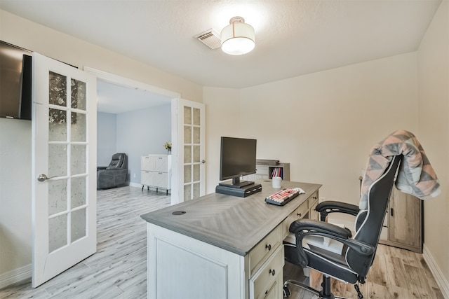 office with light wood-type flooring, french doors, and a textured ceiling