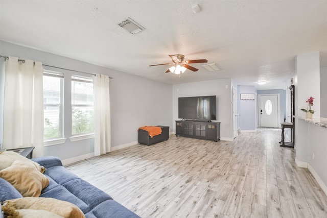 living room with a textured ceiling, light wood-type flooring, and ceiling fan