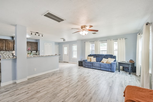 living room featuring ceiling fan, a textured ceiling, light wood-type flooring, and rail lighting