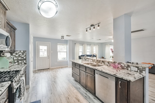 kitchen featuring stainless steel appliances, sink, a textured ceiling, light wood-type flooring, and decorative backsplash