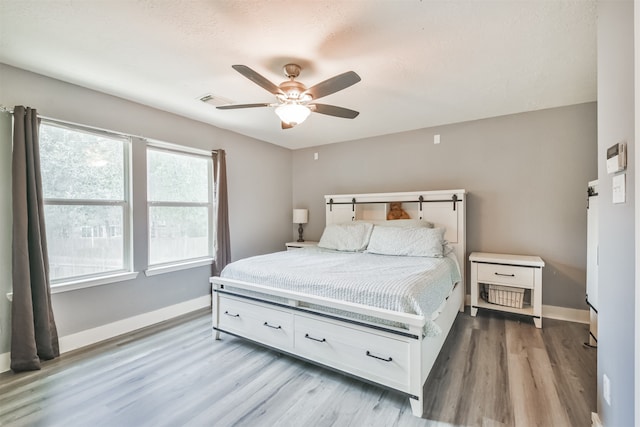 bedroom with wood-type flooring, ceiling fan, and a textured ceiling