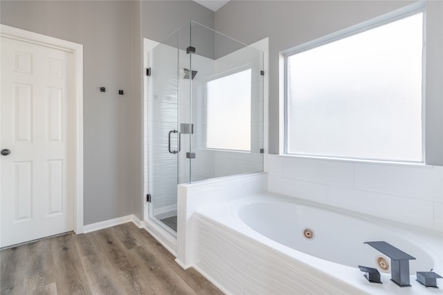 bathroom featuring wood-type flooring and shower with separate bathtub