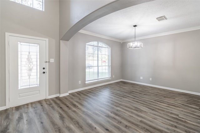 entrance foyer featuring a textured ceiling, dark hardwood / wood-style flooring, crown molding, and an inviting chandelier