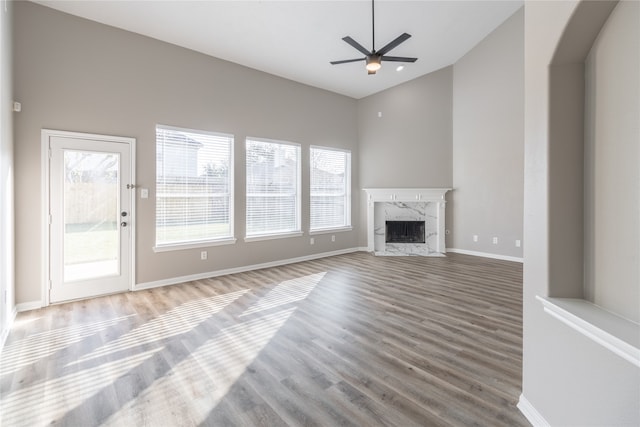 unfurnished living room with a fireplace, wood-type flooring, high vaulted ceiling, and ceiling fan