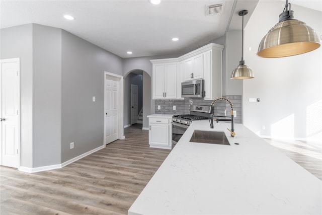 kitchen with white cabinets, decorative light fixtures, sink, and stainless steel appliances