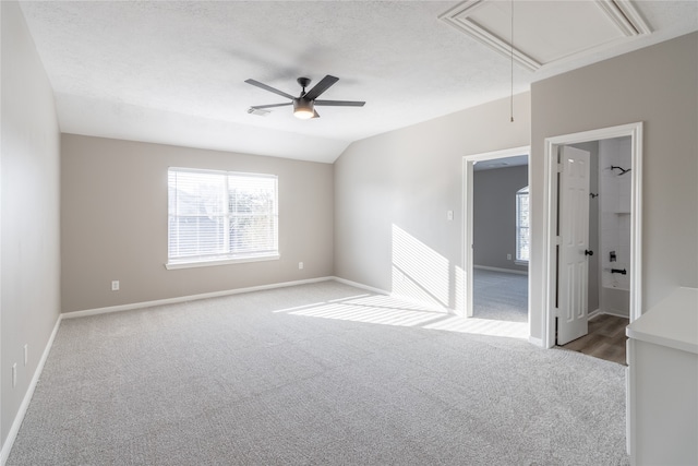 carpeted spare room featuring ceiling fan, lofted ceiling, and a textured ceiling