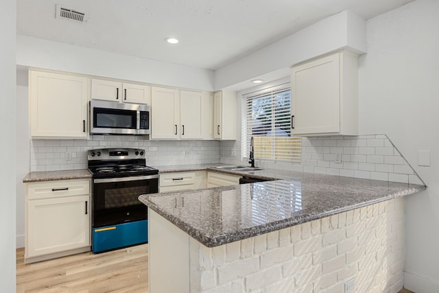 kitchen featuring stainless steel appliances, light hardwood / wood-style floors, stone countertops, kitchen peninsula, and white cabinets