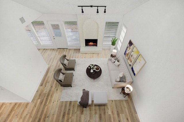 living room featuring a fireplace, light hardwood / wood-style floors, plenty of natural light, and a textured ceiling