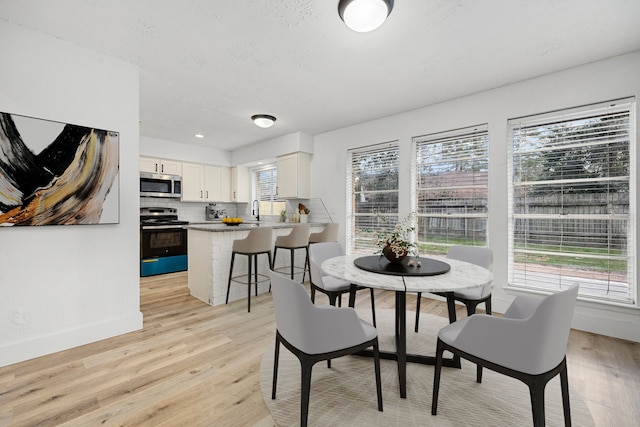 dining room featuring sink and light hardwood / wood-style flooring