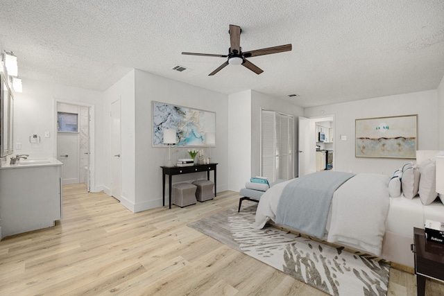 bedroom featuring light wood-type flooring, a textured ceiling, and ceiling fan