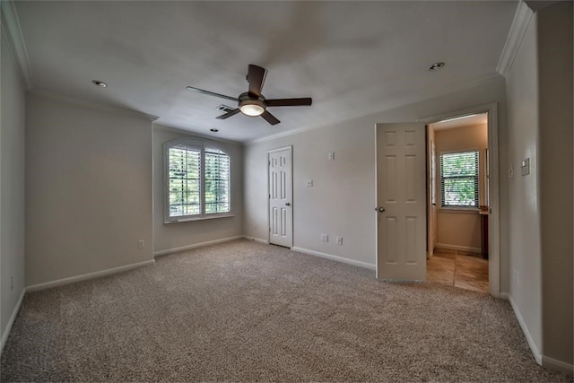 unfurnished bedroom featuring crown molding, light colored carpet, multiple windows, and ceiling fan