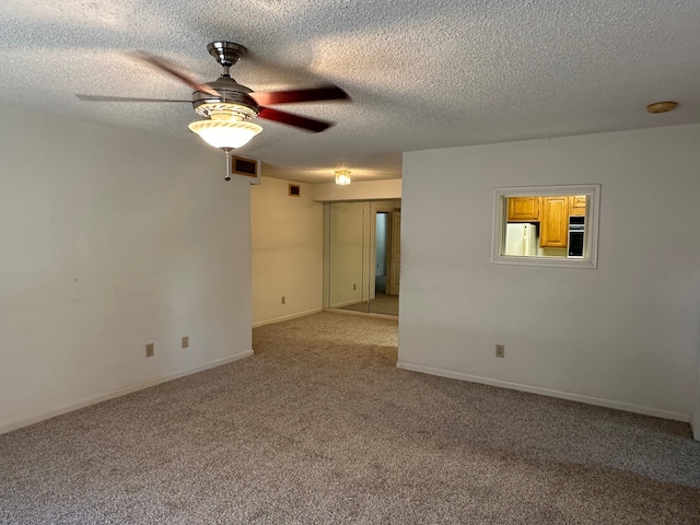 carpeted spare room featuring ceiling fan and a textured ceiling