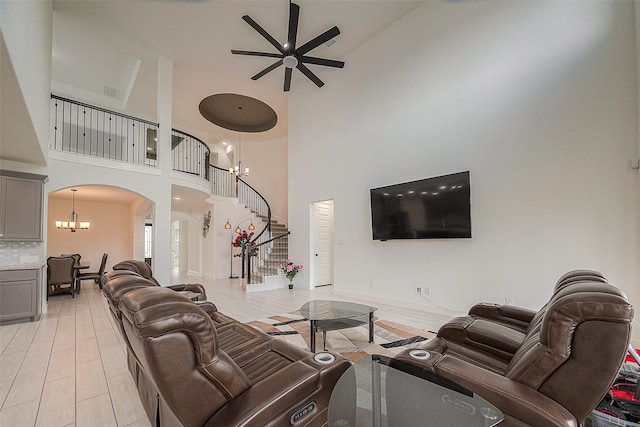 living room featuring ceiling fan with notable chandelier and a towering ceiling