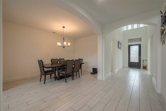 dining area with light wood-type flooring and a notable chandelier