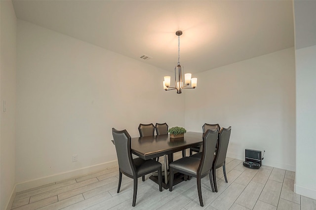 dining room with light wood-type flooring and an inviting chandelier