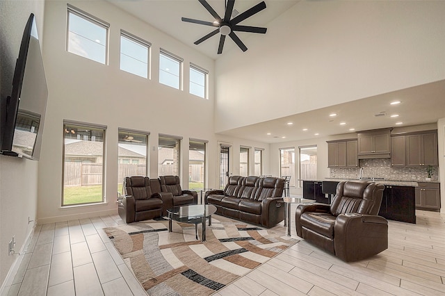 living room with a towering ceiling, ceiling fan, and a healthy amount of sunlight