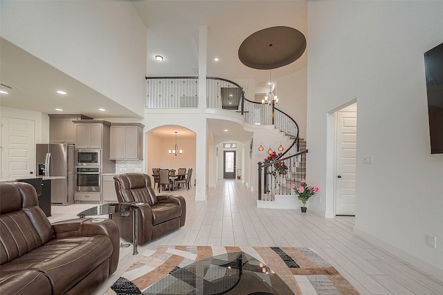 living room with a high ceiling, light hardwood / wood-style flooring, and a notable chandelier