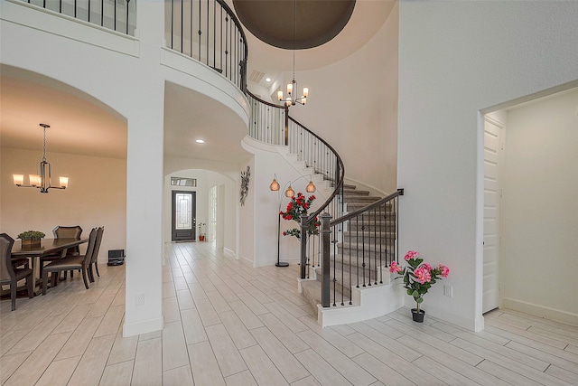 entryway with a high ceiling, a chandelier, and light hardwood / wood-style floors