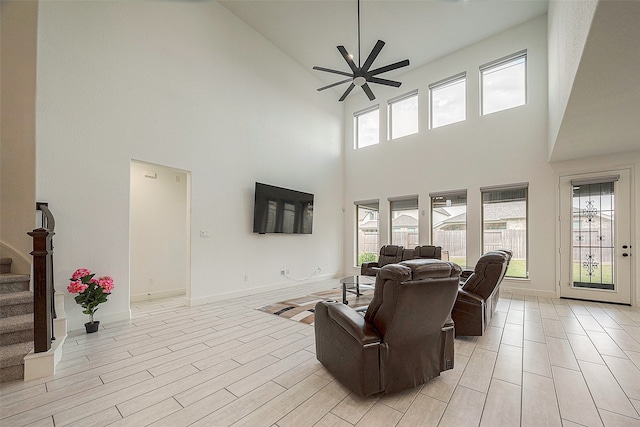 living room with a towering ceiling, ceiling fan, plenty of natural light, and light hardwood / wood-style floors