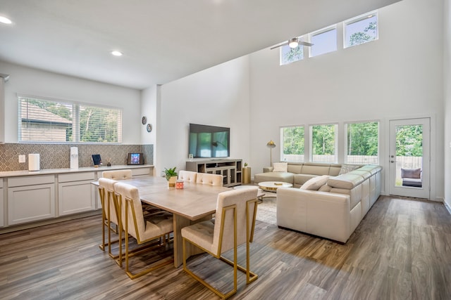 dining room with a wealth of natural light, a towering ceiling, and light hardwood / wood-style floors