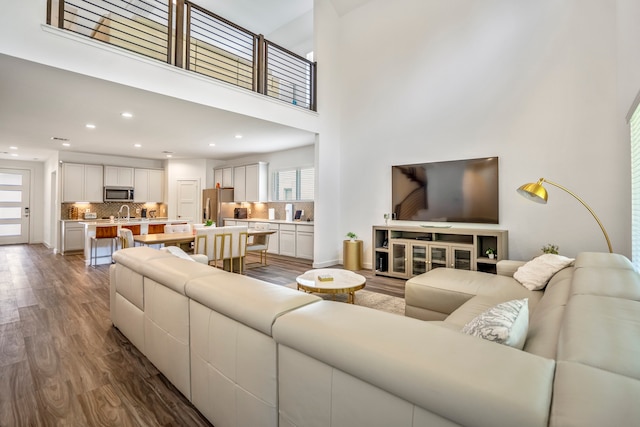 living room with a towering ceiling and dark hardwood / wood-style floors