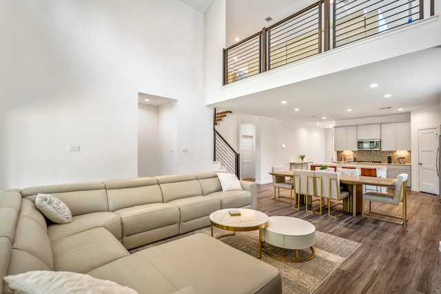 living room with sink, dark hardwood / wood-style floors, and a towering ceiling