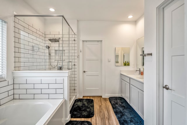 bathroom with a wealth of natural light, independent shower and bath, vanity, and wood-type flooring