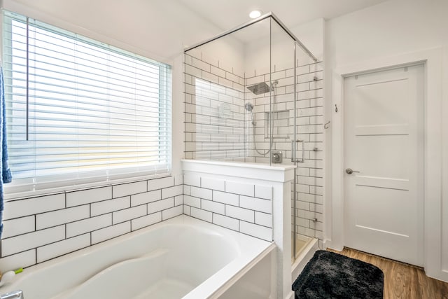 bathroom featuring plus walk in shower and hardwood / wood-style flooring